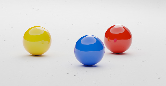 A shiny yellow, blue, and red sphere on a sleek white surface