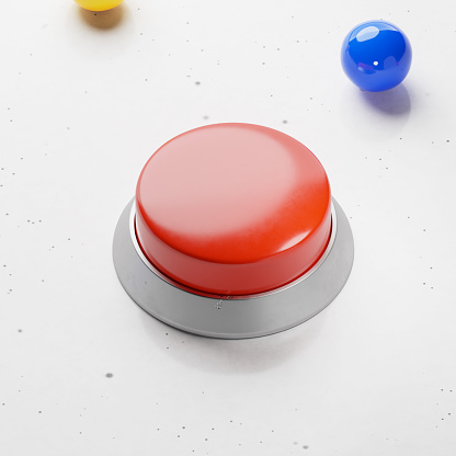 High angle view of large red button sitting on white tabletop