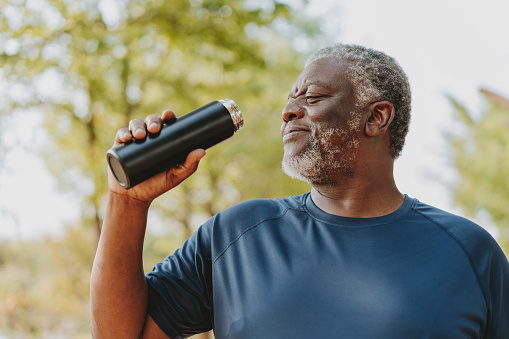 Portrait of a senior man drinking water exercising