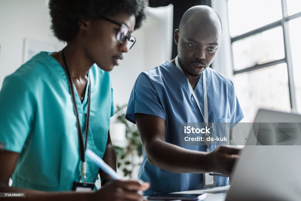 Two medical workers at work using laptop and discussing Medical Occupation Stock Photo