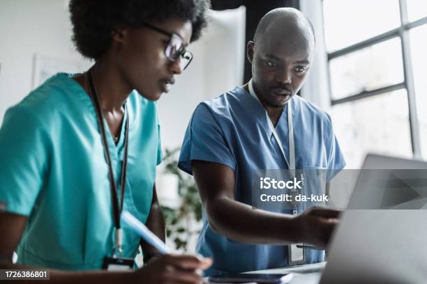 Two Medical Workers At Work Using Laptop And Discussing Stock Photo - Download Image Now