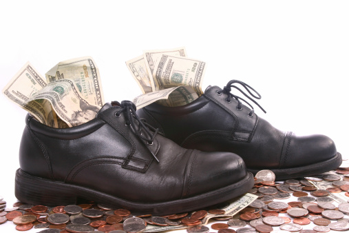 A pair of men's dress shoes standing in a pile of money.