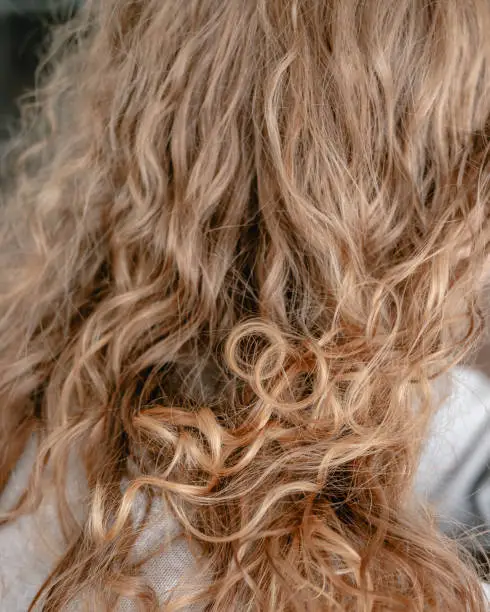 Close up of naturally curly blonde hair with frizz