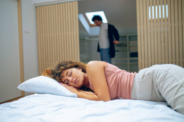 istock Woman is sleeping in bed while man is getting dressed in closet 1726402464