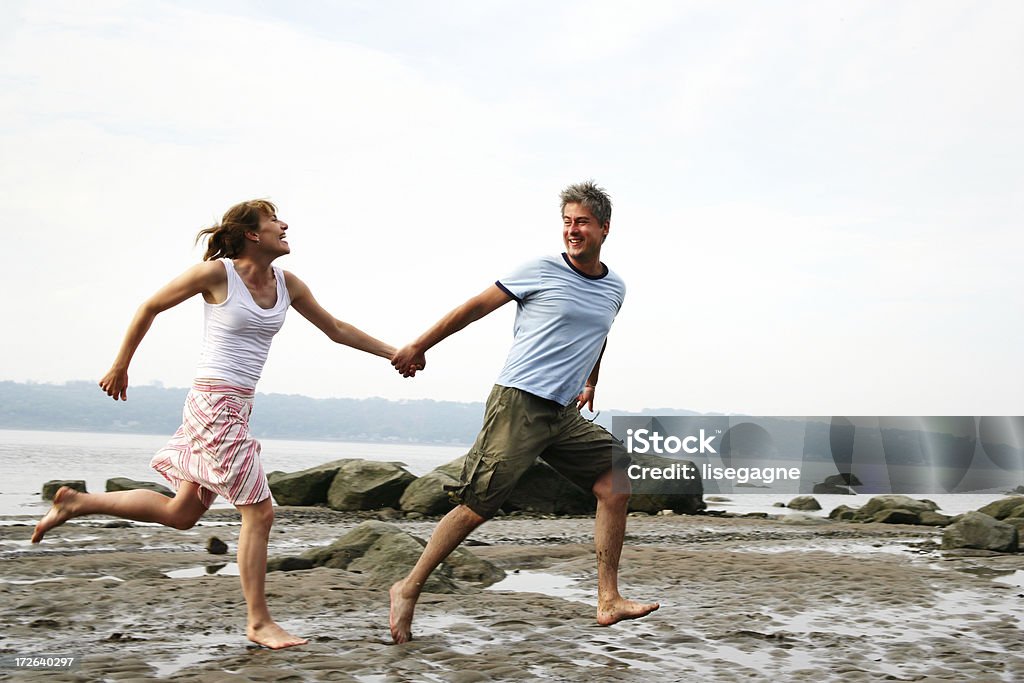 Couple running on the beach Some parts are in motion, DOF. Adult Stock Photo
