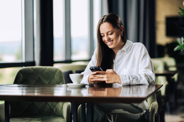 istock Happy brunette sitting in a cafe and using the phone 1726404767