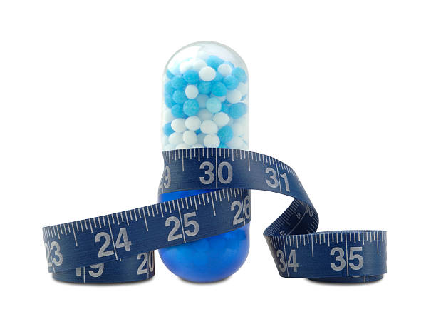 Diet Pill Diet Pill with Measuring Tape on White. diet pills stock pictures, royalty-free photos & images