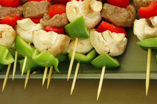 close up on a  bunch of raw kabobs on a plate waiting to be grilled