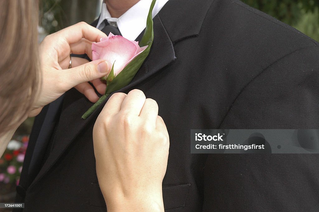 boutonniere1 woman pinning a pink boutonniere on man's jacket Boutonniere Stock Photo