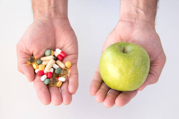 istock man's hand with one with a green apple and hand with pills 1726415732