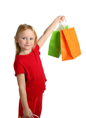 young girl holding up colorful shopping bags isolated on white