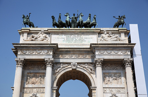 Arco della Pace or Arch of Peace with statues and bas-relief on blue sky in Milan, Italy
