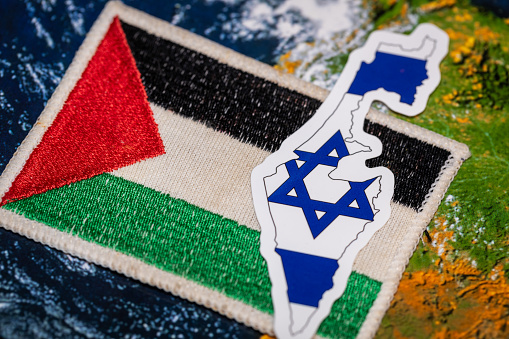 Flags of Israel and Palestine on a rough wall.