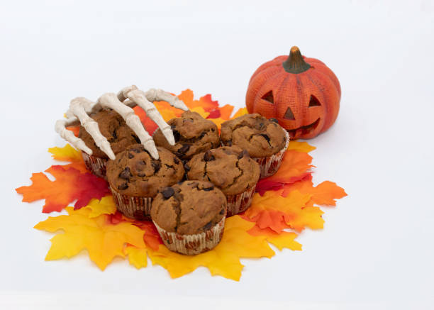 Halloween Welcomed with Pumpkin Muffins, Smiling Pumpkin, and Skeleton Hand stock photo