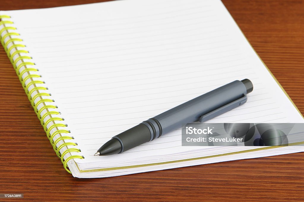 Yellow notebook. An open, ruled notebook with yellow spiral binding. Desk Stock Photo