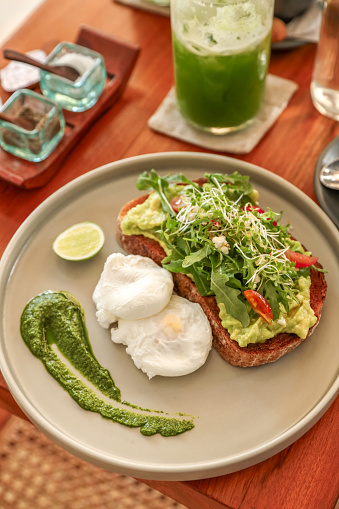 Brunch Breakfast with Avocado Toast Eggs Benedict and green Fruit smoothie juice at Bali Coffee Shop Restaurant