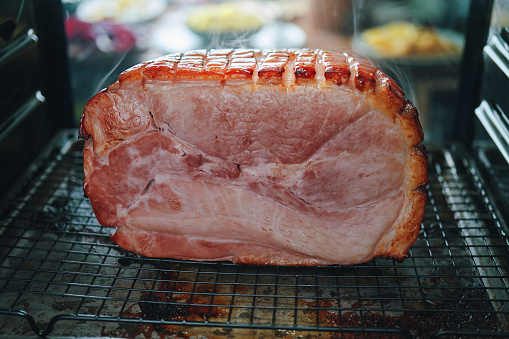 Christmas composition with baked ham on dark background. Traditional food concept. Top view, flat lay, copy space