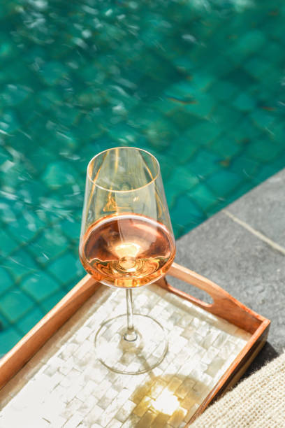 rosé wine glass on wood tray at tropical hotel resort swimming pool stock photo