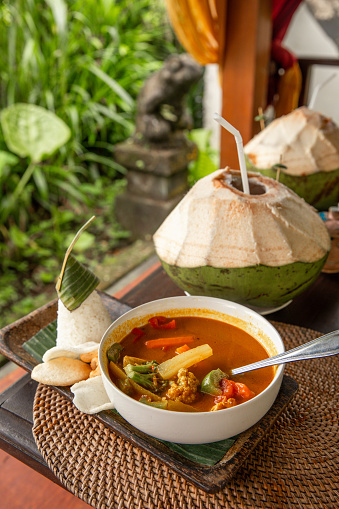 Indonesian chicken Curry dish Kari Ayam in bowl with vegetables and coconut in Bali outdoor restaurant