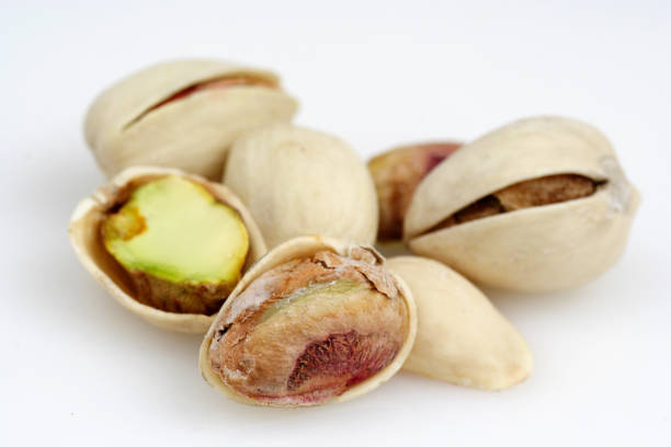 istock Fresh whole pistachio nuts cracked open on white background 172646328
