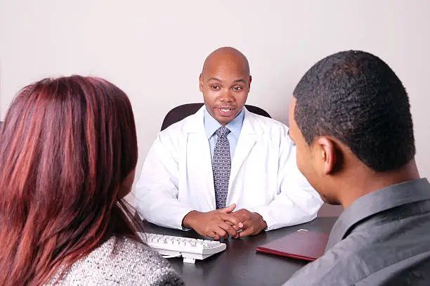 "A doctor talks with a couple. Fertility counselling, therapy, medical advice, etc."