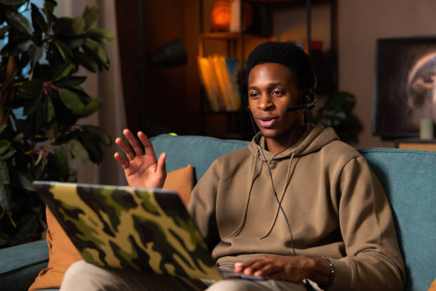 istock Happy African American guy using a tablet computer to video conference with friends or a partner. He is waving and grinning while doing so. The scene is of a house interior 1726473649