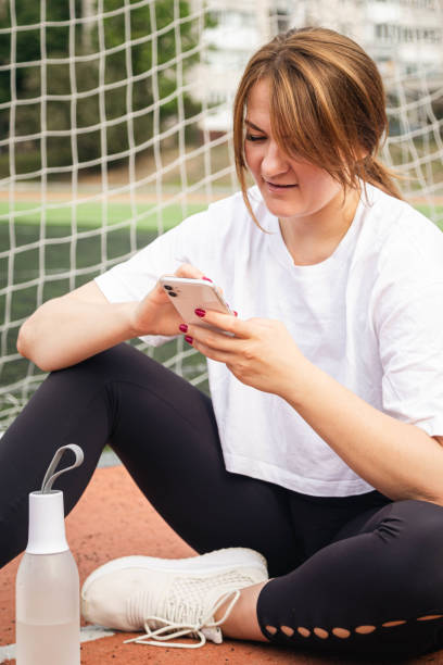 istock A woman uses a smartphone while sitting on a treadmill at the stadium. 1726480662