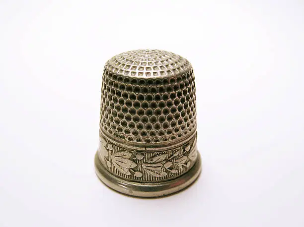 "A very old thimble, white background."