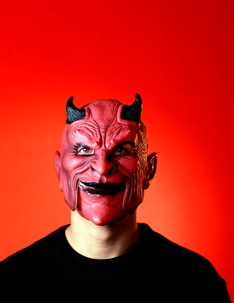 istock Man with a red devil mask with horns on against red back 172648575