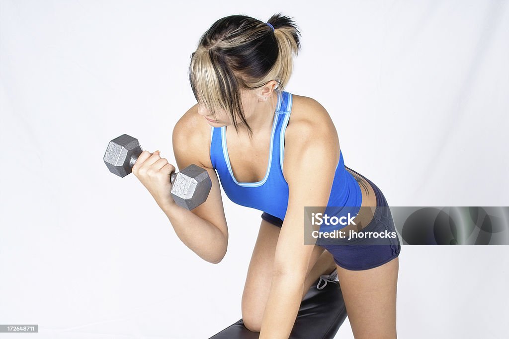 Attractive Young Woman Lifting Weights Young woman curling a hex dumbell. Hair Back Stock Photo