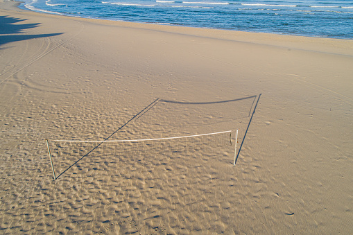 Aerial drone view of a beach volleyball net on a beach