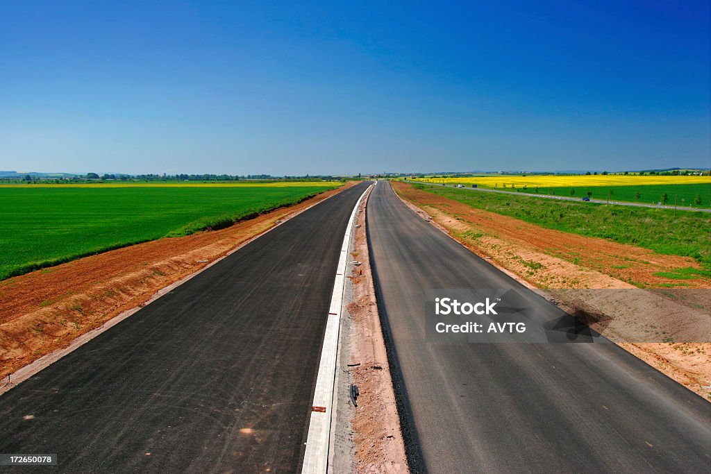 Highway Under Construction Newly build highway, lines meeting in the infinity Agricultural Field Stock Photo