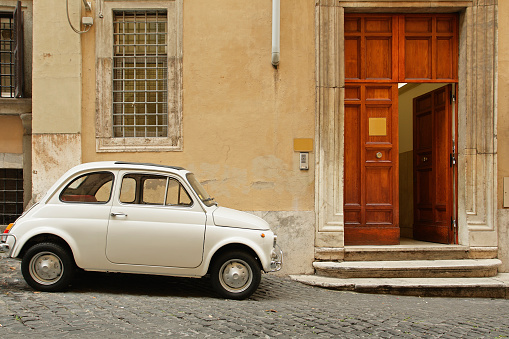Small coupe parked near a doorway on a cobblestone street