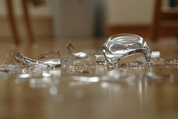 Close up of broken glass on floor Glass has fallen on the floor and broke up. Very shallow DOF. broken stock pictures, royalty-free photos & images