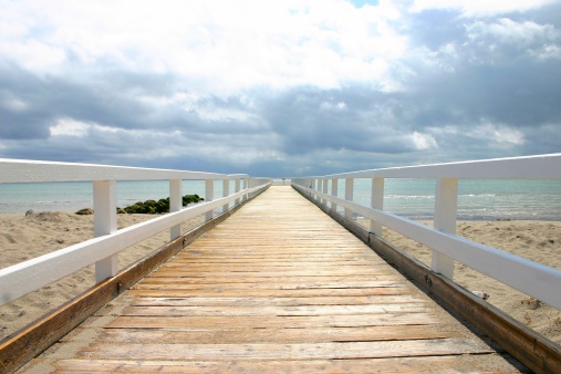 Old wooden seabridge at baltic sea after a heavy rain shower with sun peaking at the bridge