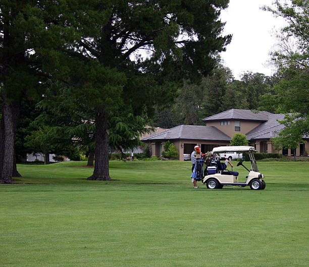 Afternoon of Golf "A man and his son getting ready to hit their ball n front of the golf cart, with an executive home in the background." cameron montana stock pictures, royalty-free photos & images