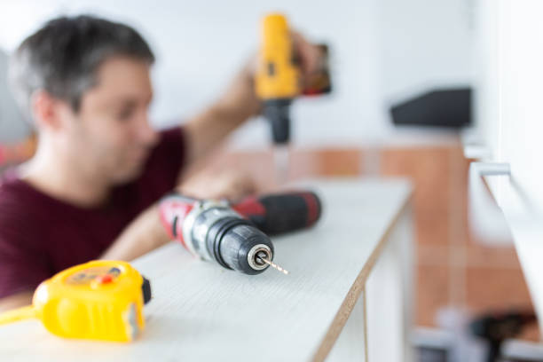 istock Close up of electric drill with carpenter working in the background. Kitchen assembly concept. 1726516178
