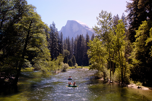 A pair of rafts on the Merced river with Half Dome in the background.