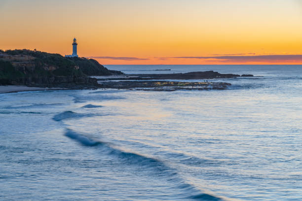 Sunrise seascape with low cloud bank and Norah Head Lighthouse from Soldiers Beach on the Central Coast, NSW, Australia.