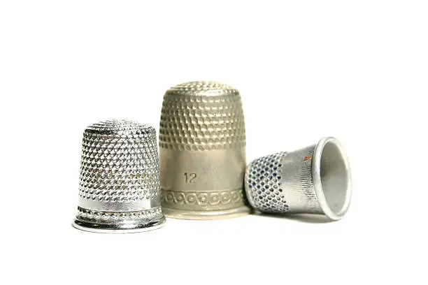 Isolated on a white background. Focus on the thimble on the left hand side is strongest.