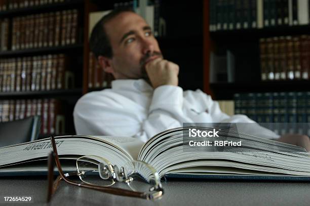 Man Thinking At His Desk By An Open Book In A Library Stock Photo - Download Image Now