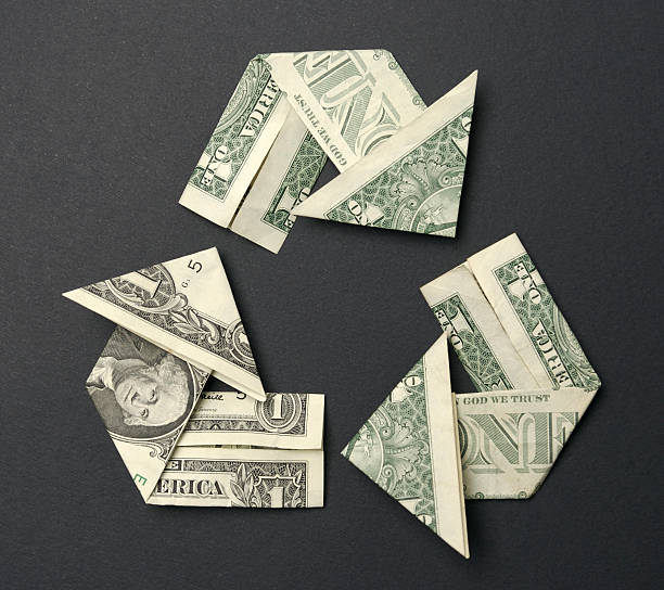 Dollar Bills Folded into Recycle Symbol Origami on Black Recycle symbol fashioned from dollar bills on a black background making money origami stock pictures, royalty-free photos & images