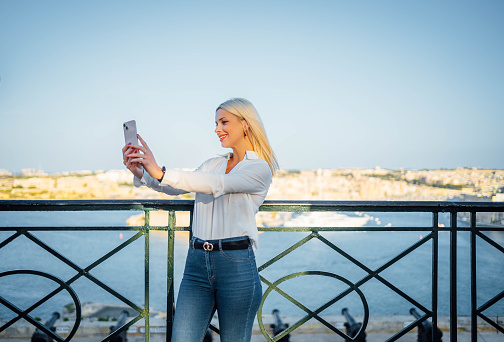 Young smiling woman taking selfies in Malta