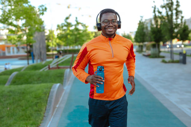 istock A handsome African American man cheerfully running, while looking at the camera and listening to music 1726551551