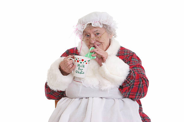 Stealing cookies & milk Mrs Claus Character Humor. Sneaky Mrs. Claus stealing Santa's milk and cookies. santa claus expressions shhh stock pictures, royalty-free photos & images