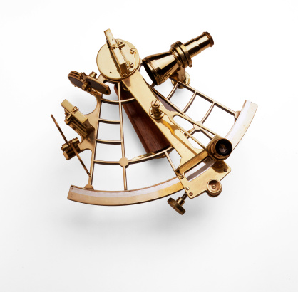 Antique nautical sextant photographed against a white background with a soft shadow.