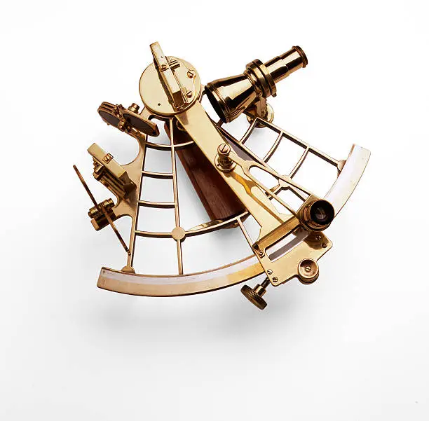 Antique nautical sextant photographed against a white background with a soft shadow.