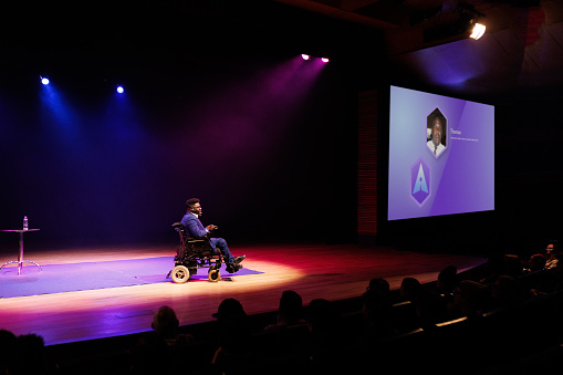 Man in a wheelchair giving a speech in a conference