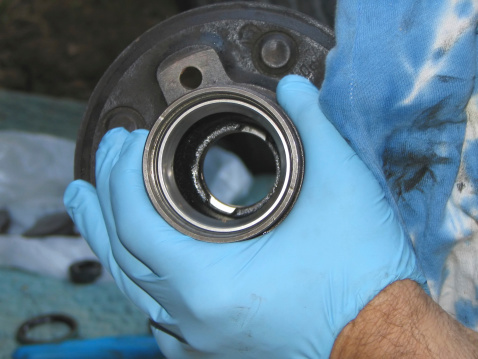 Close up of hand in blue glove holding automobile wheel bearing hubSee other skilled jobs: