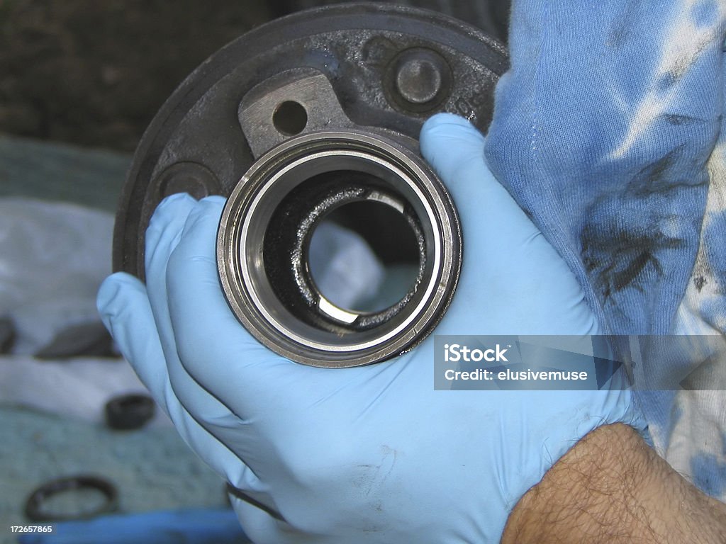 Auto Mechanic Repairs the Bearing Hub Close up of hand in blue glove holding automobile wheel bearing hubSee other skilled jobs: Ball Bearing Stock Photo